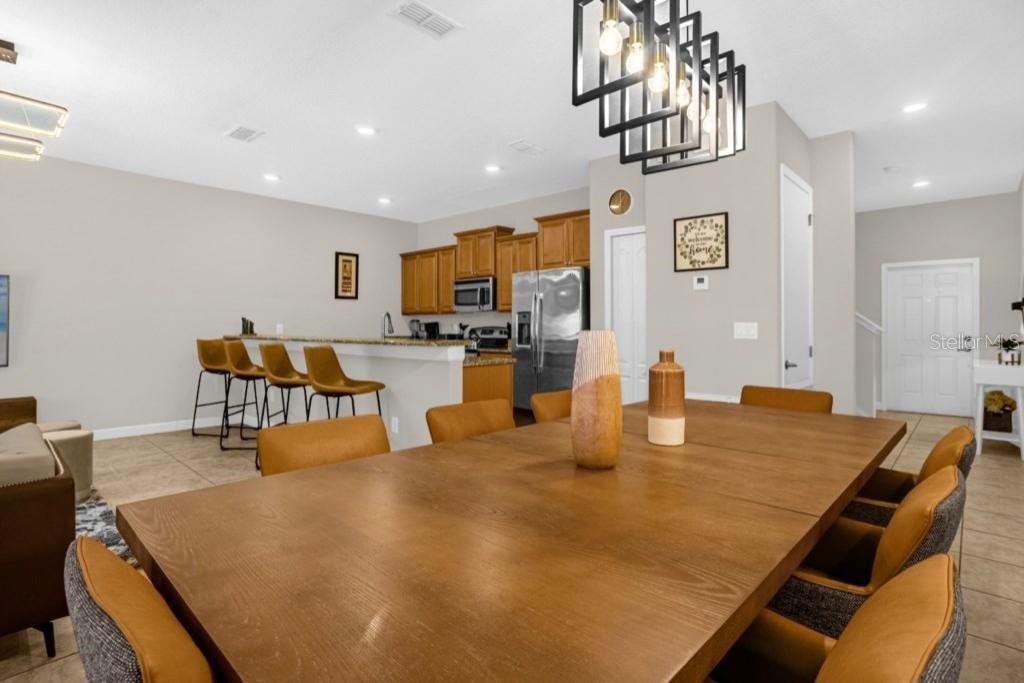 A dining area with a large wooden table and chairs adjacent to an open kitchen — 2955 BANANA PALM DRIVE, KISSIMMEE, FL