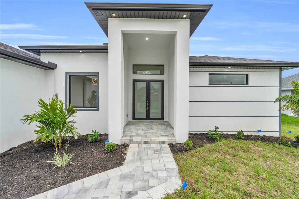 The exterior of a modern house features a white facade, double glass doors, and pavers — 15401 AQUA CIRCLE, PORT CHARLOTTE, FL