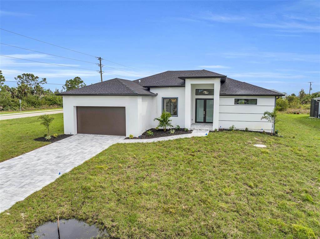 A modern single-story house with a white exterior, dark roof, and a paved driveway — 15401 AQUA CIRCLE, PORT CHARLOTTE, FL