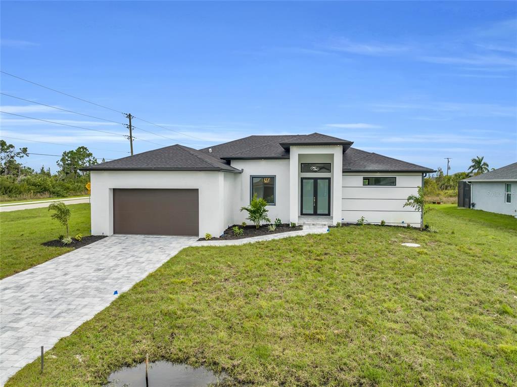 A modern single-story house with a white stucco exterior, dark roof, and paved driveway — 15401 AQUA CIRCLE, PORT CHARLOTTE, FL