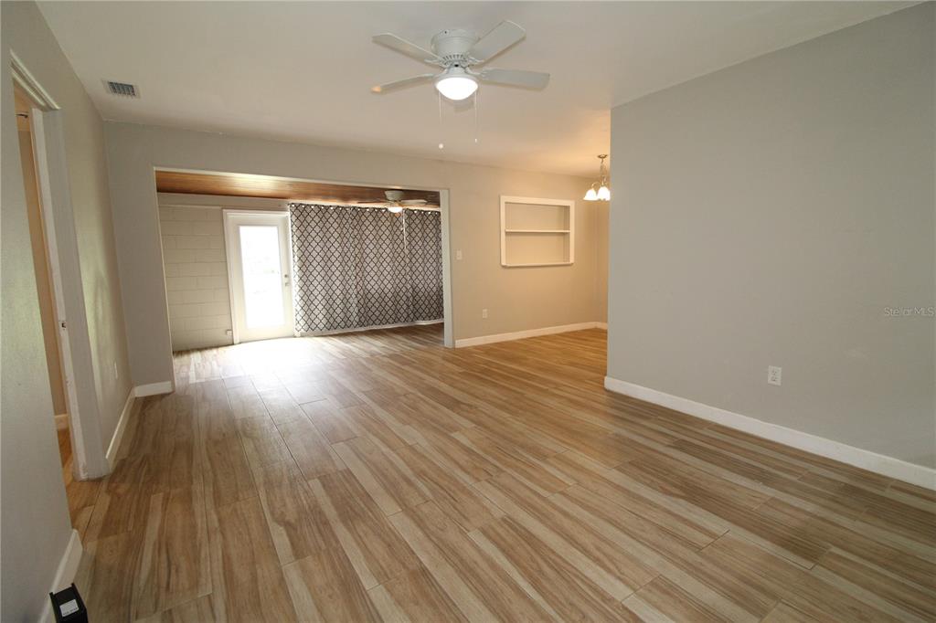 A living room with wood-look tile flooring, a ceiling fan, and an adjacent sunroom — 207 LAKE VIEW DRIVE, SANFORD, FL
