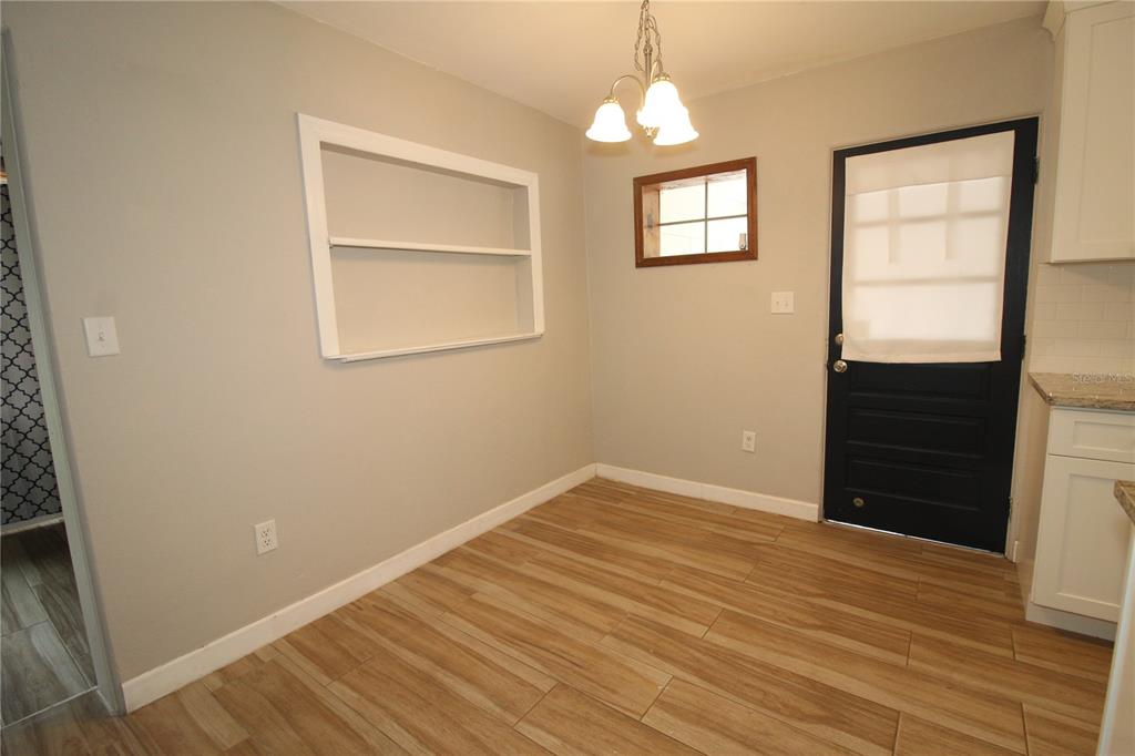 A dining area features light gray walls, wood-look tile flooring, a built-in shelf, and a door — 207 LAKE VIEW DRIVE, SANFORD, FL