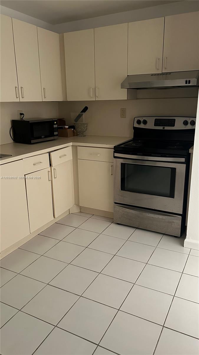 A kitchen features white cabinets, stainless steel appliances, and light-colored tiled flooring — 9962 N KENDALL DR # 7, Miami FL 33176, MIAMI, FL