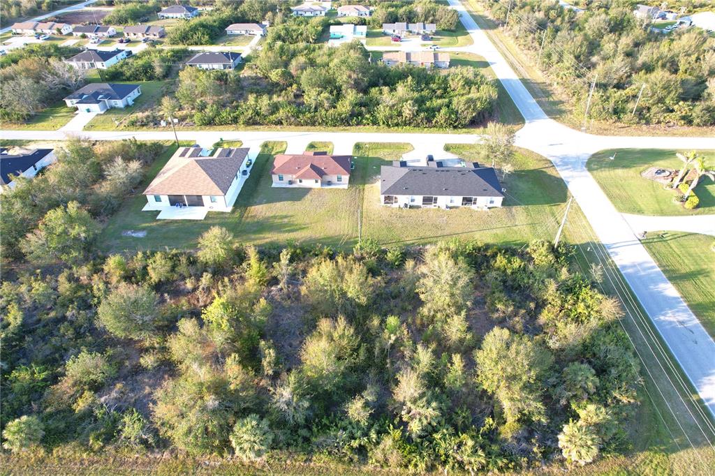 An aerial view shows a vacant wooded lot adjacent to several single-family homes — 12266 NEWGATE AVENUE, PORT CHARLOTTE, FL