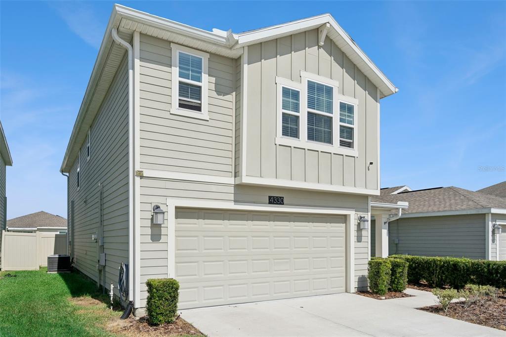 A two-story house with light-colored siding and a two-car garage under a clear sky — 4330 SUNNY CREEK PLACE, KISSIMMEE, FL