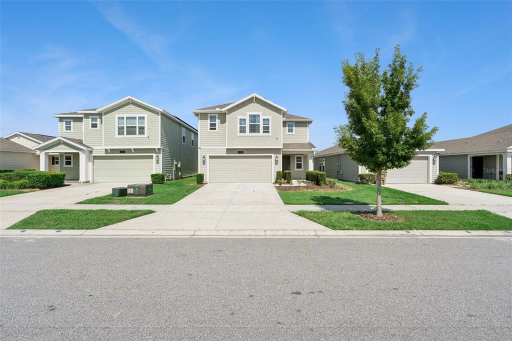 A street view of two suburban two-story houses with light green siding and concrete driveways — 4330 SUNNY CREEK PLACE, KISSIMMEE, FL