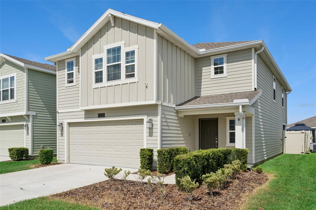 A two-story house with light-colored siding, a two-car garage, and a small front garden — 4330 SUNNY CREEK PLACE, KISSIMMEE, FL