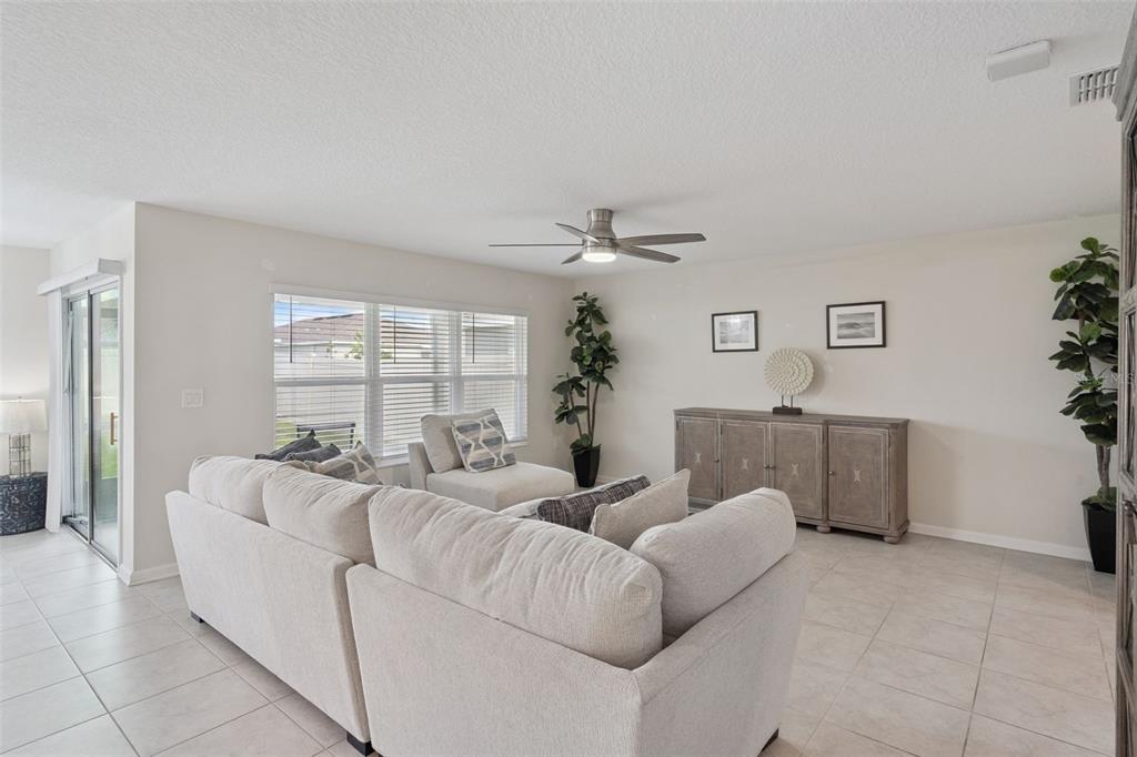 A living room features a light-colored sectional sofa, a console table, and a ceiling fan — 4330 SUNNY CREEK PLACE, KISSIMMEE, FL