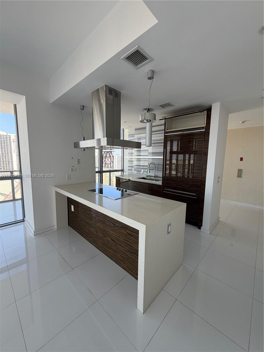 A modern kitchen features a white quartz island, dark wood cabinetry, and stainless steel appliances — 1100 Biscayne Blvd # 2605, Miami FL 33132, MIAMI, FL