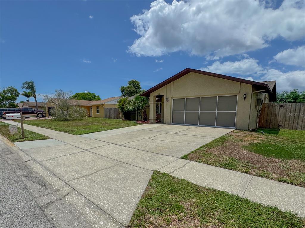 A single-story house with a beige stucco exterior and a large, multi-panel garage door — 3127 DOLE STREET, HOLIDAY, FL