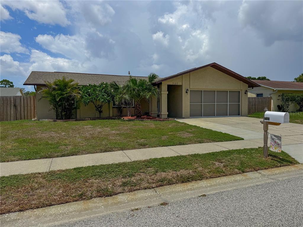 A single-story house with a tan stucco exterior, a two-car garage, and a front lawn — 3127 DOLE STREET, HOLIDAY, FL