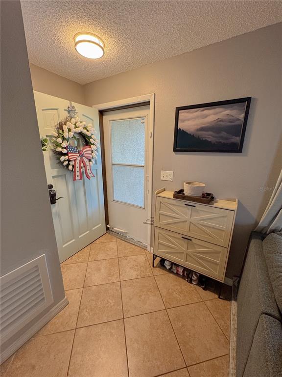 An entryway features a light-colored door with a wreath, tile flooring, and a shoe cabinet — 3127 DOLE STREET, HOLIDAY, FL