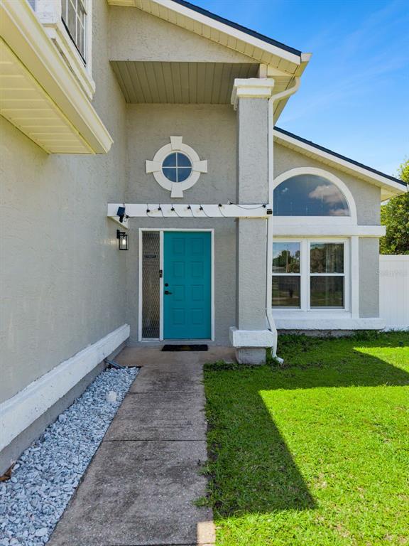 A teal front door is centered under a pergola on the exterior of a house — 622 COLORADO WOODS COURT, ORLANDO, FL