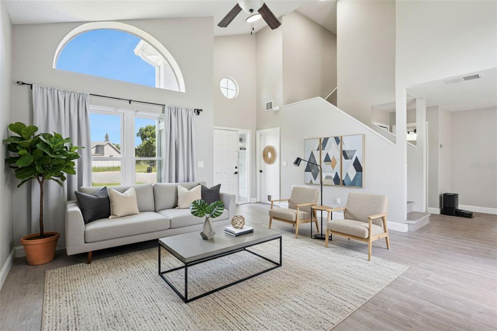 A bright living room features a gray sofa, two armchairs, and a large arched window — 622 COLORADO WOODS COURT, ORLANDO, FL