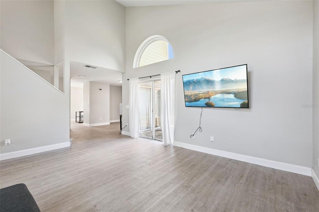 A living room features light wood-look flooring, a vaulted ceiling, and a wall-mounted television — 622 COLORADO WOODS COURT, ORLANDO, FL