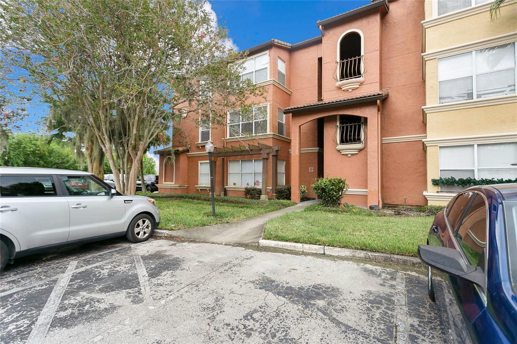 A multi-story apartment building with stucco exterior, balconies, and a parking lot in front — 5148 CONROY ROAD UNIT 12, ORLANDO, FL