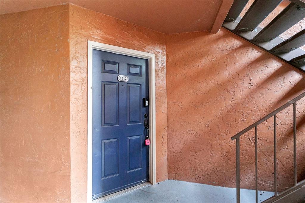 A blue front door with a lockbox is set into a textured orange exterior wall — 5148 CONROY ROAD UNIT 12, ORLANDO, FL