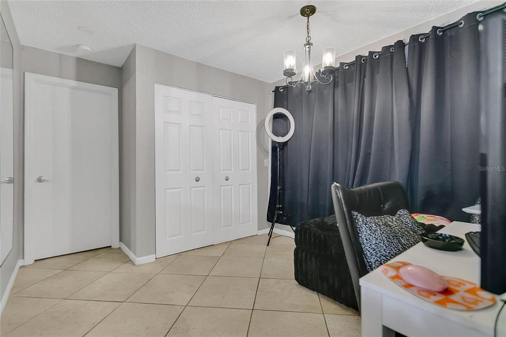 A room with tiled floors, white doors, a black chair, and dark curtains — 5148 CONROY ROAD UNIT 12, ORLANDO, FL