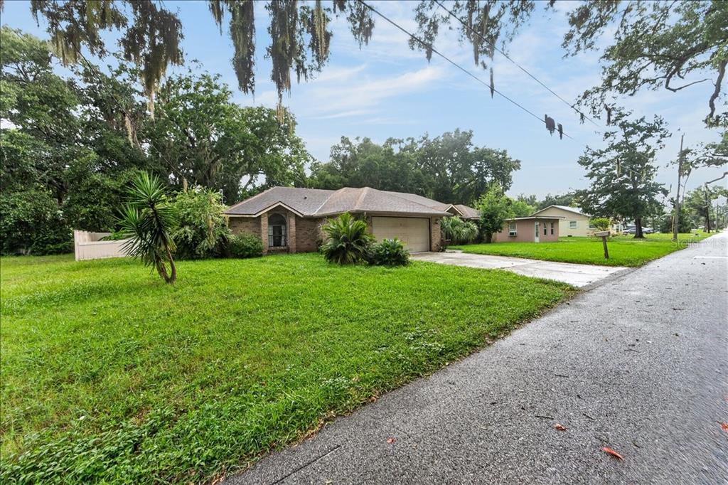 A single-story brick house with a two-car garage sits on a grassy lot with trees — 344 N FREDERICK AVENUE, DAYTONA BEACH, FL