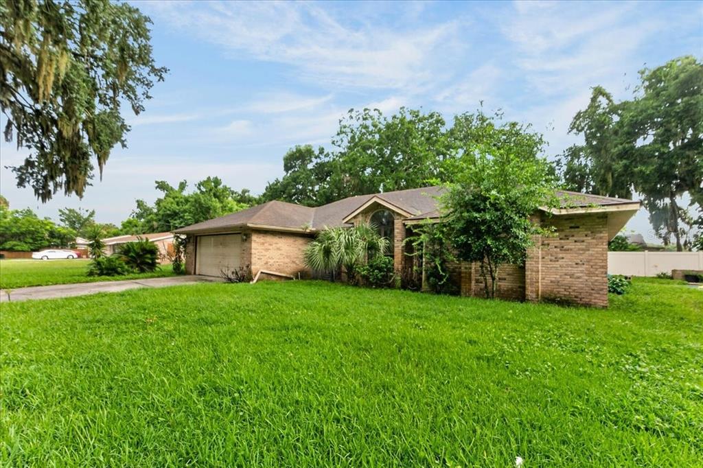 A single-story brick house with a two-car garage sits on a large, grassy lawn — 344 N FREDERICK AVENUE, DAYTONA BEACH, FL