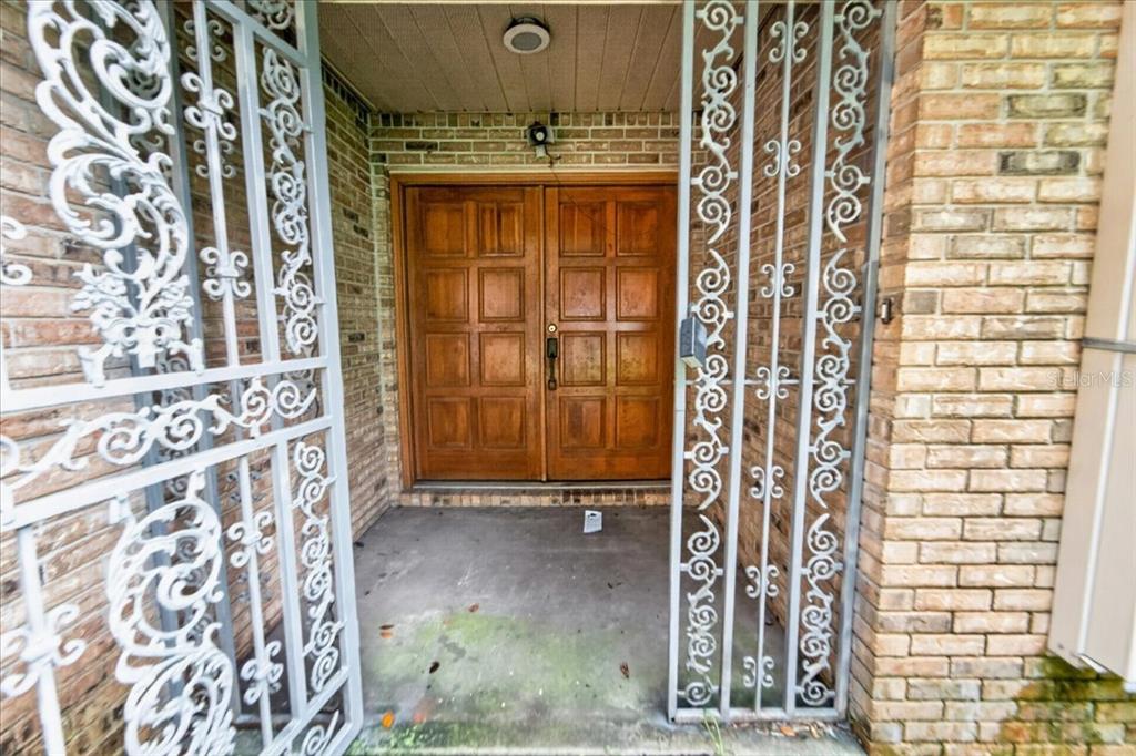 A covered entryway features double wooden doors behind decorative white metal security gates — 344 N FREDERICK AVENUE, DAYTONA BEACH, FL