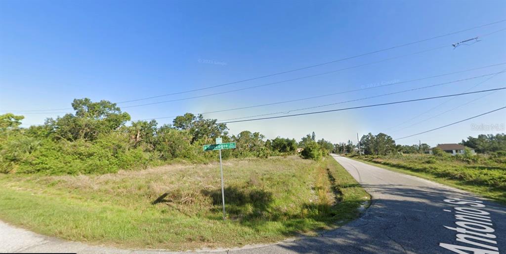 A vacant, grassy corner lot at the intersection of two paved roads with scattered trees — Lot 1, 2, 3 & 4 ANTONIO STREET, NORTH PORT, FL