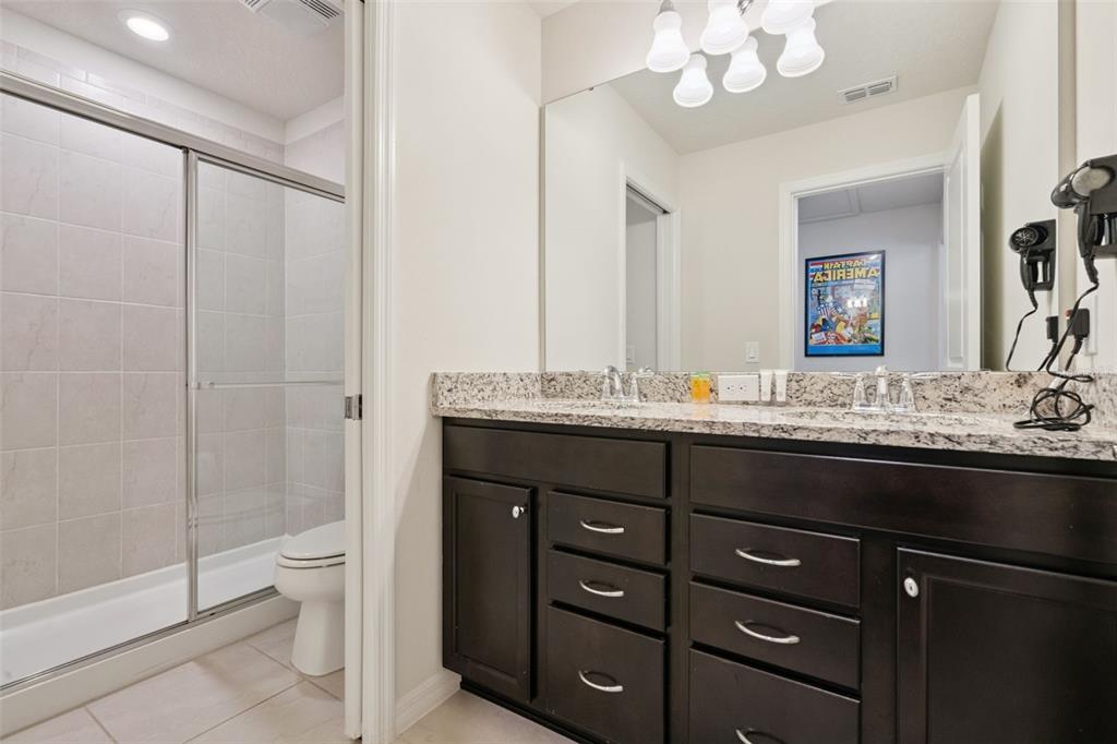 A bathroom features a dark wood vanity with a granite countertop and a glass-enclosed shower — 1876 SUMMER DRIVE, DAVENPORT, FL