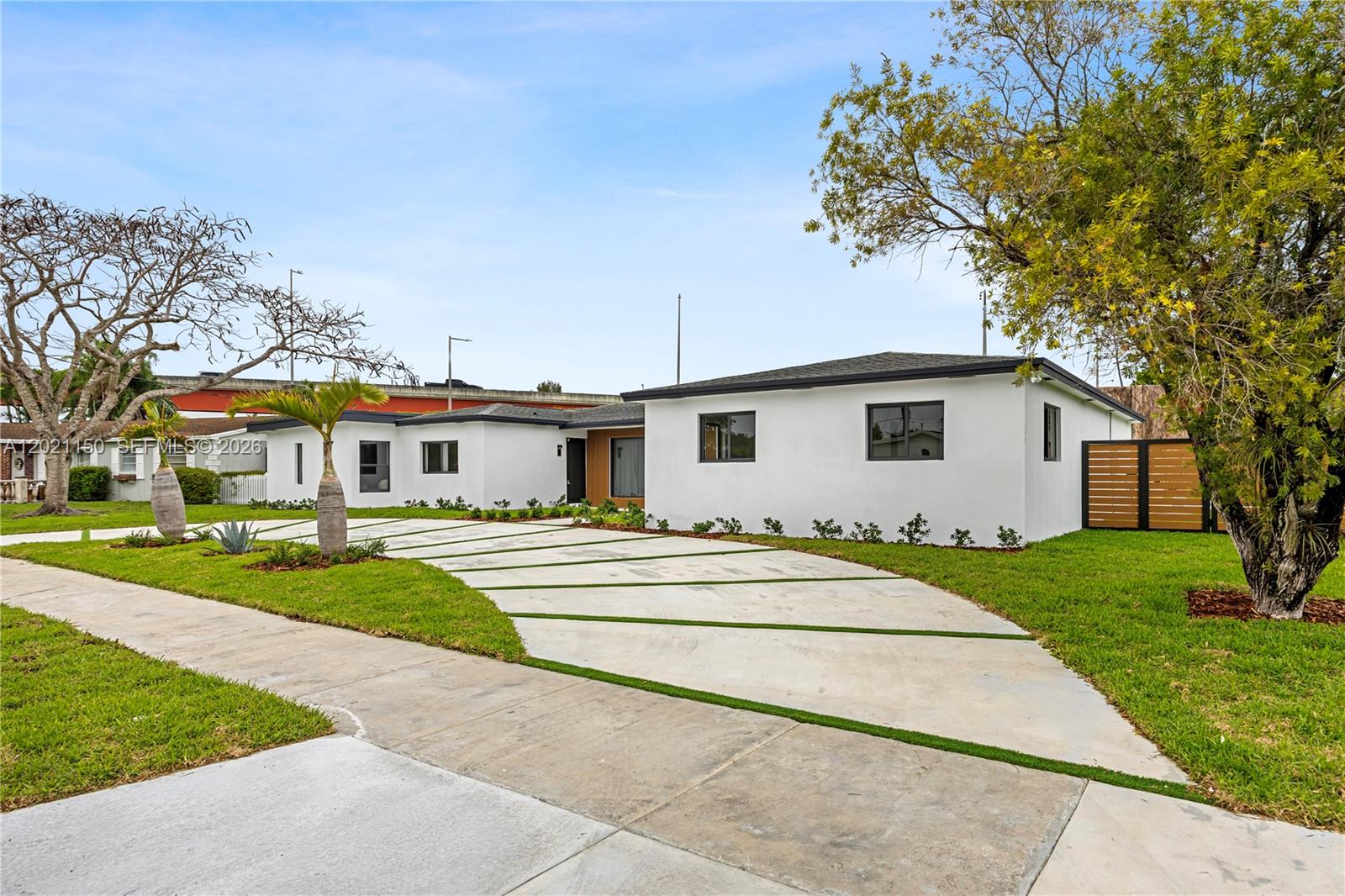 A white, single-story house features a modern concrete driveway with grass strips and landscaping — 9261 SW 80th Ter, Miami FL 33173, MIAMI, FL