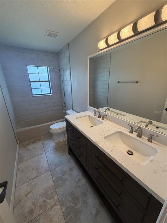 A bathroom features a double vanity with a quartz countertop, tile flooring, and a tub-shower — 5741 SE 21ST LANE, OCALA, FL