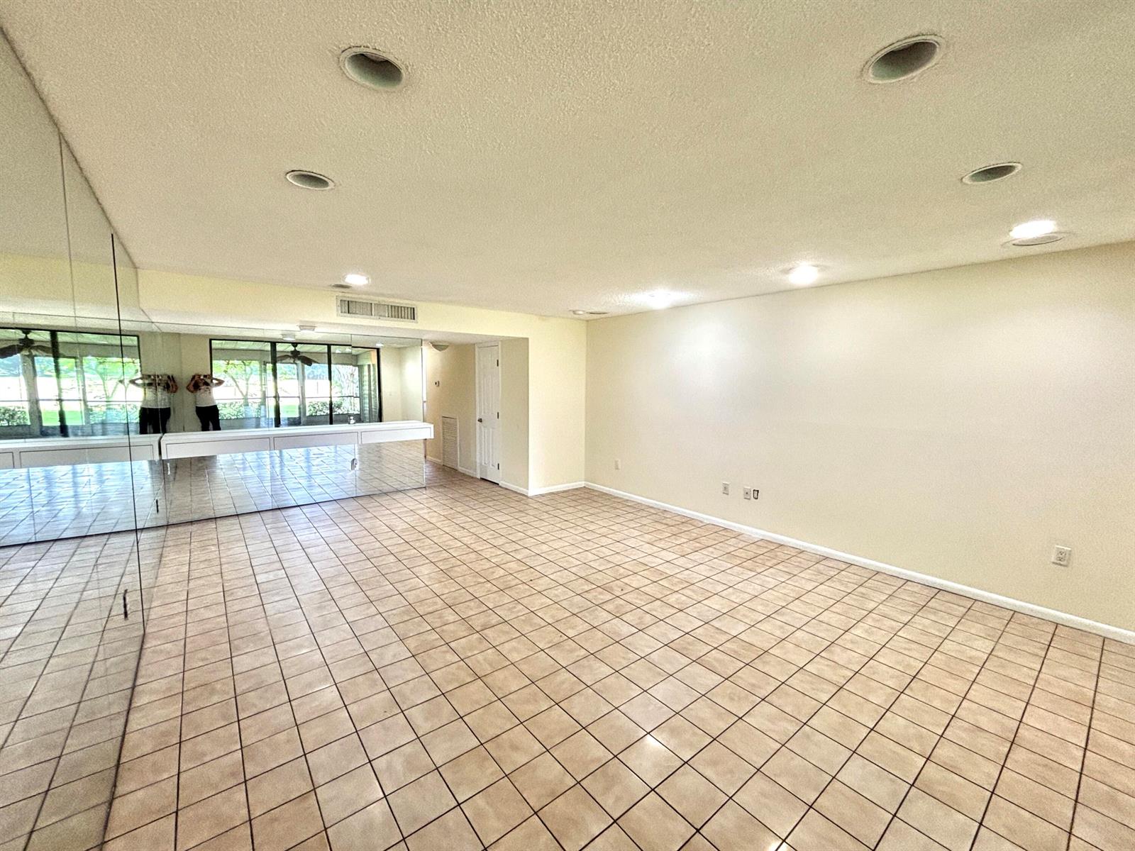 A spacious room features light-colored tile flooring, a mirrored wall, and sliding glass doors — 4807 Esedra Court, Lake Worth FL 33467, LAKE WORTH, FL