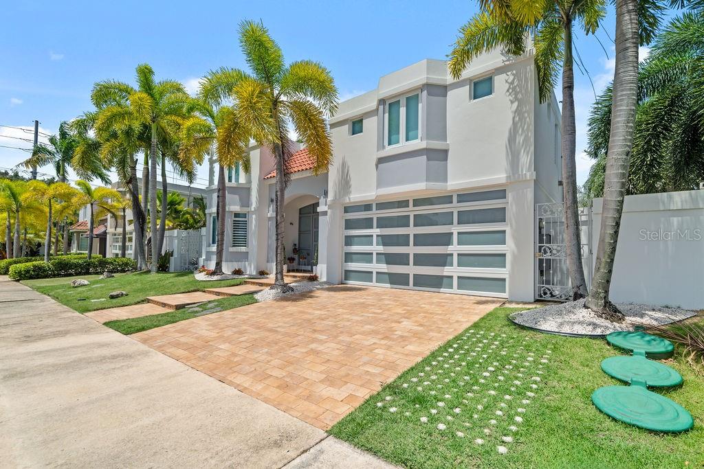 A two-story white house with a multi-paneled garage door and palm trees in the front yard — H2 MAR DE BERING UNIT 638, DORADO, PR