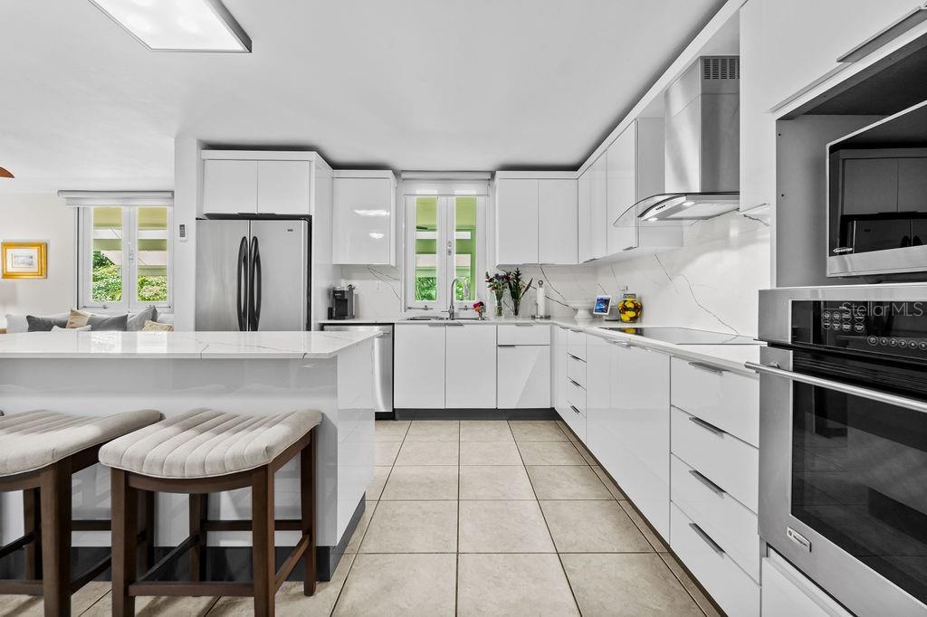 A modern kitchen features white cabinets, stainless steel appliances, and a white marble-topped island — H2 MAR DE BERING UNIT 638, DORADO, PR