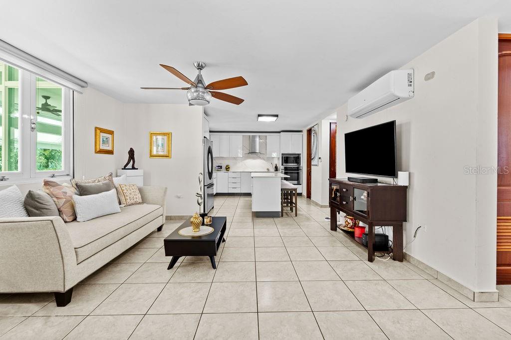 A living room with tile floors, a sofa, and a ceiling fan opens to a kitchen — H2 MAR DE BERING UNIT 638, DORADO, PR