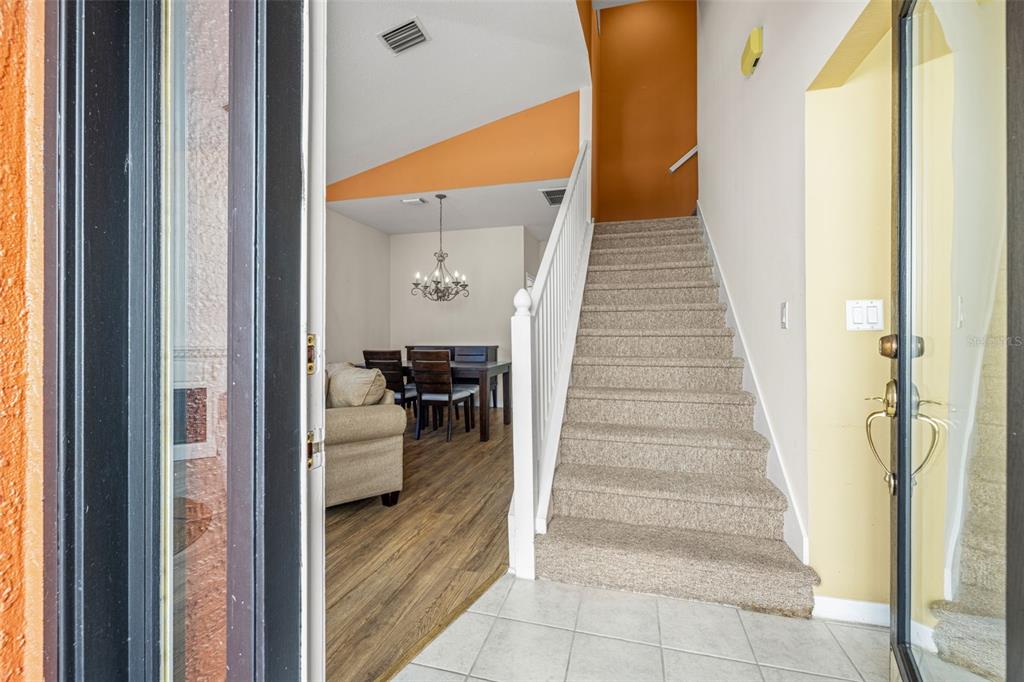 An entryway features a carpeted staircase, tile flooring, and a view into a dining area — 11016 BLAINE TOP PLACE, TAMPA, FL