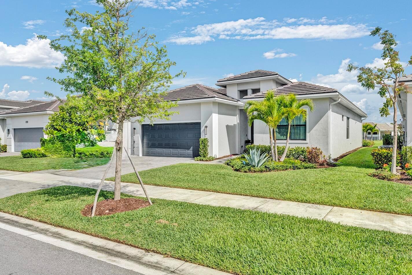 A single-story suburban house with a gray garage, tile roof, and landscaped front yard — 15647 Merritt Drive, Westlake FL 33470, WESTLAKE, FL
