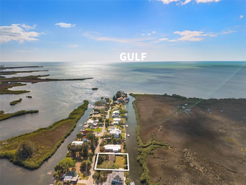 An aerial view shows a coastal neighborhood with a highlighted residential lot near water — 3037 SUNSET VISTA DRIVE, SPRING HILL, FL