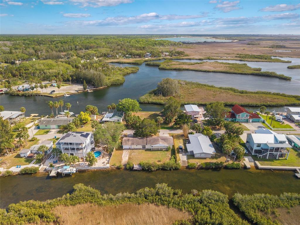 An aerial view shows waterfront houses along a canal surrounded by marshland and trees — 3037 SUNSET VISTA DRIVE, SPRING HILL, FL
