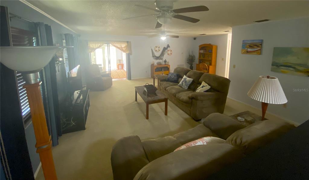 A living room features a brown sofa, a coffee table, and a ceiling fan — 829 E 12TH AVENUE, NEW SMYRNA BEACH, FL