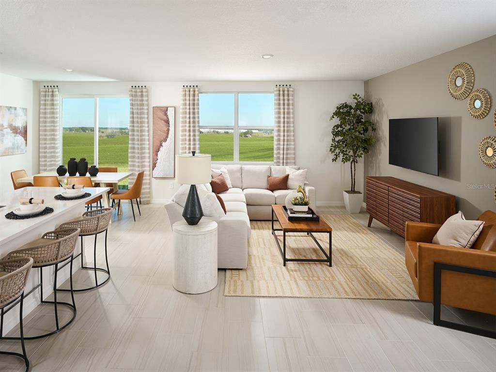A modern open-concept living and dining area features light tile floors and large windows — 12610 HOURGLASS WAY, DADE CITY, FL