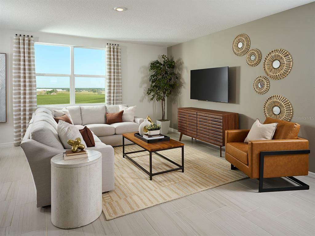 A living room features a sectional sofa, leather armchair, media console, and wall-mounted circular decor — 12610 HOURGLASS WAY, DADE CITY, FL