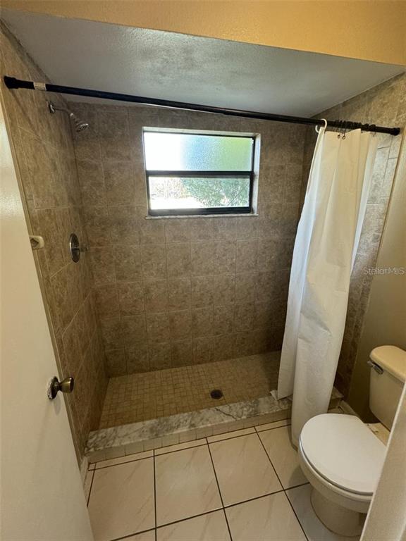 A bathroom features a tiled walk-in shower with a window and a white toilet — 913 SAN RAFAEL WAY, KISSIMMEE, FL