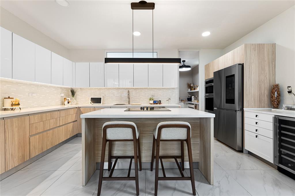 A modern kitchen features white upper cabinets, wood-tone lower cabinets, a central island, and stainless appliances — 153 RIVER TERRACE, JUNCOS, PR