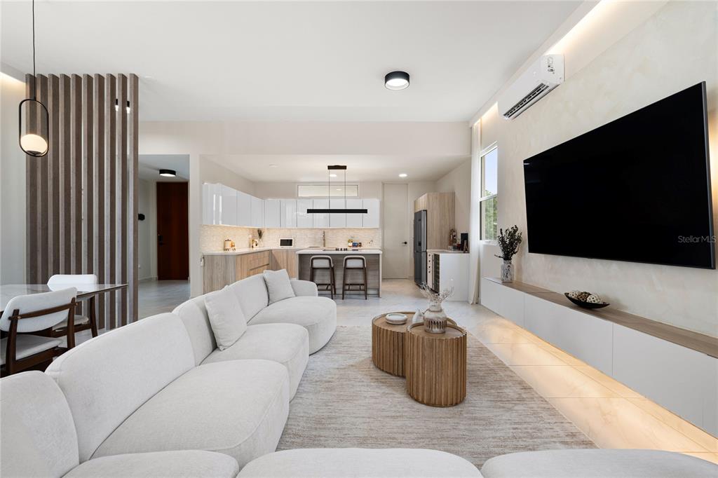 A modern open-concept living room features a white sectional sofa, wood coffee tables, and kitchen — 153 RIVER TERRACE, JUNCOS, PR