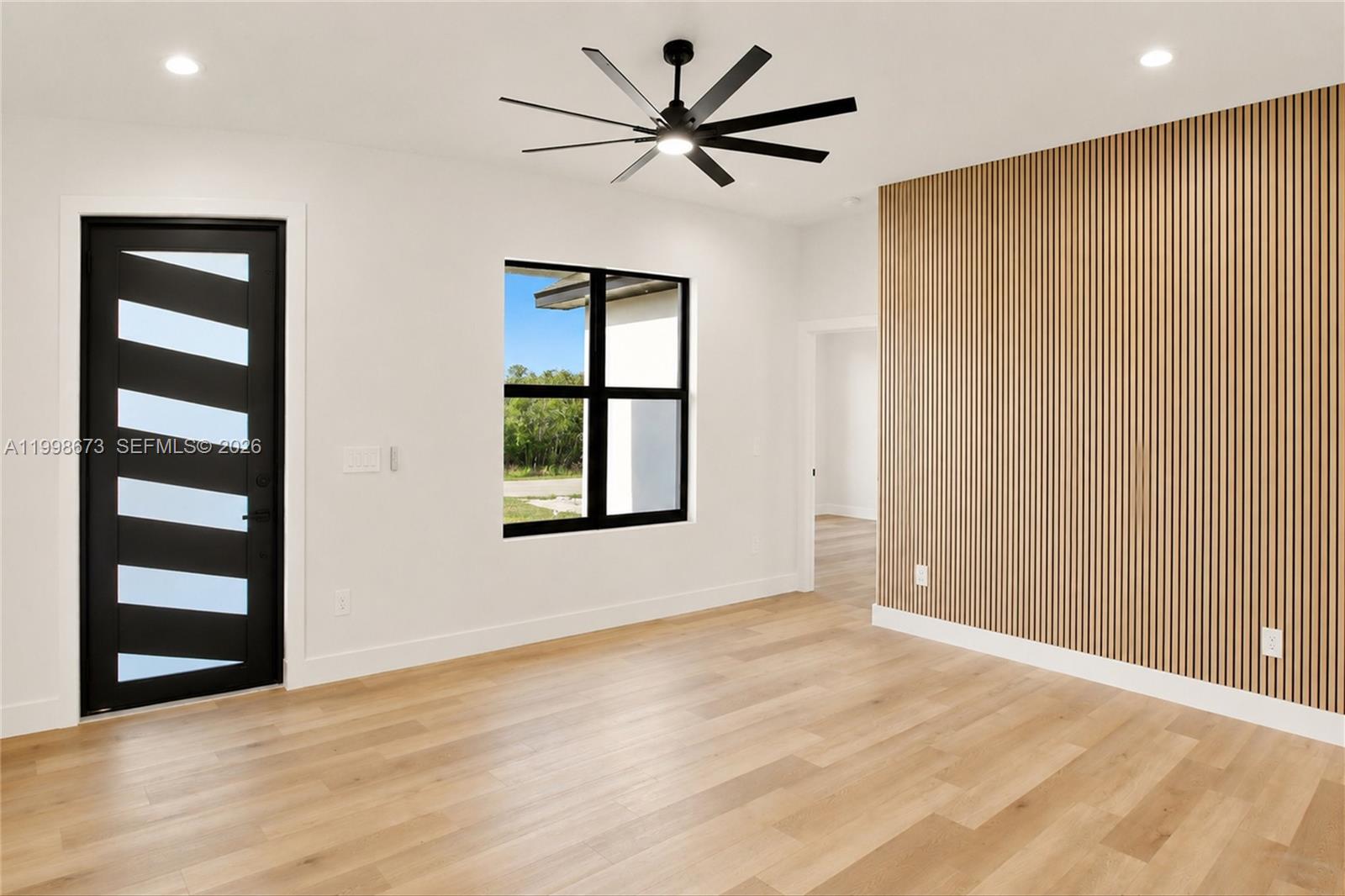 A room features light wood flooring, a black-framed door, a window, and a slatted wall — 7322 Granada Boulevard, Sebring FL 33872, SEBRING, FL