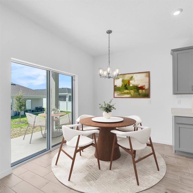 A dining area features a round wooden table, four white chairs, and a sliding glass door — 5820 CLIFFBOW LOOP, LEESBURG, FL