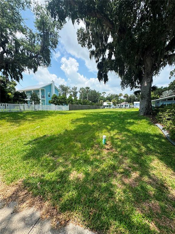 A grassy vacant lot features a utility pipe and large trees under a blue sky — 622 N RIVERSIDE DRIVE, NEW SMYRNA BEACH, FL