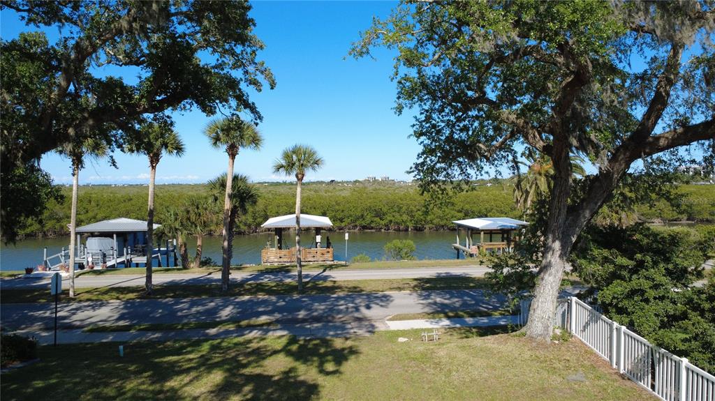 An elevated view of a waterfront street with boat docks, palm trees, and lush vegetation — 622 N RIVERSIDE DRIVE, NEW SMYRNA BEACH, FL
