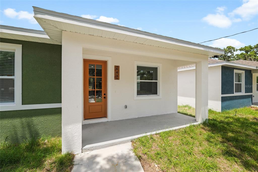A white covered porch features a wooden front door and a single window — 643 W 9TH STREET, LAKELAND, FL