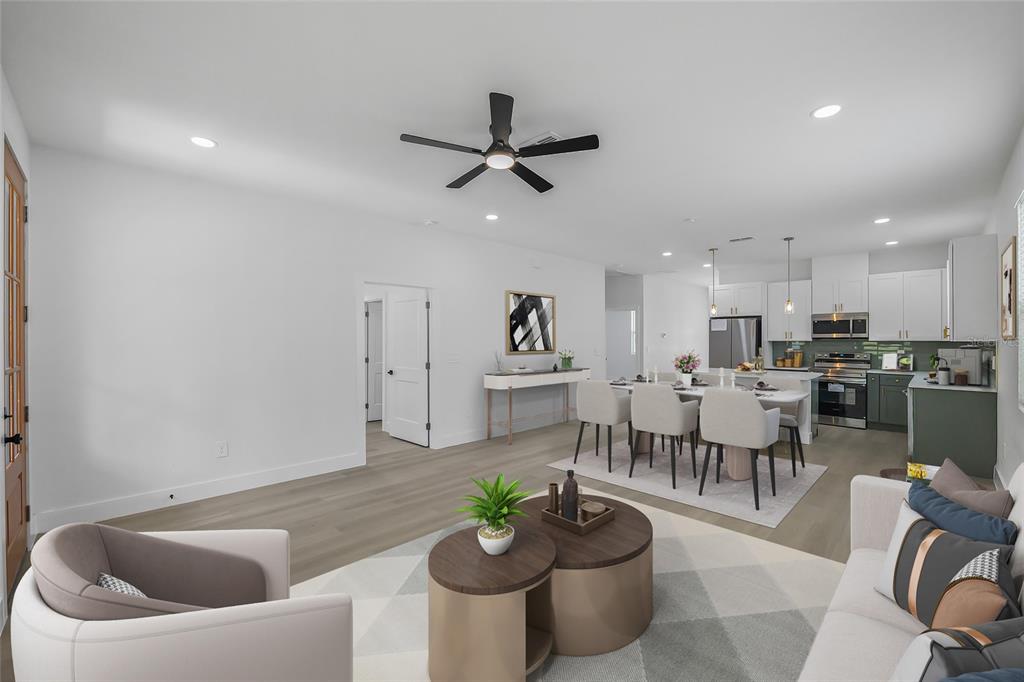 An open-concept living and dining area features light wood floors, white walls, and modern furniture — 643 W 9TH STREET, LAKELAND, FL