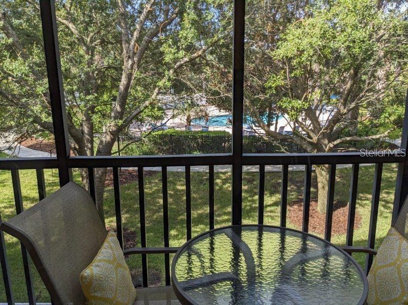 A screened-in balcony features a small glass table and chairs overlooking a swimming pool — 510 RUM RUN UNIT 510, DAVENPORT, FL